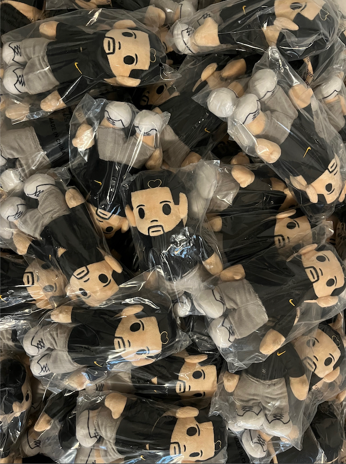 Drake plushies in clear packaging on a black background
