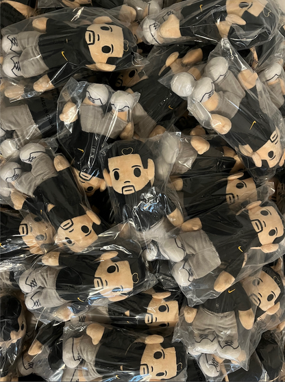 Drake plushies in clear packaging on a black background